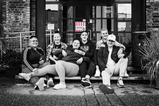 Kuusi nuorta istuu rennosti portaalla